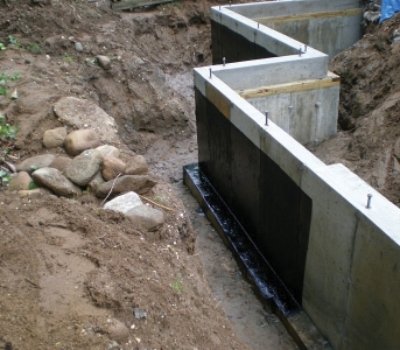 Foundation waterproofing system applied to concrete retaining walls before backfilling